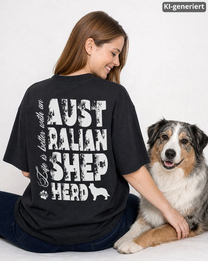 KI-generiertes Modelbild: Frau trägt schwarzes oversized Shirt mit weißem „Life is better with an Australian Shepherd“-Rückendruck neben Australian Shepherd.