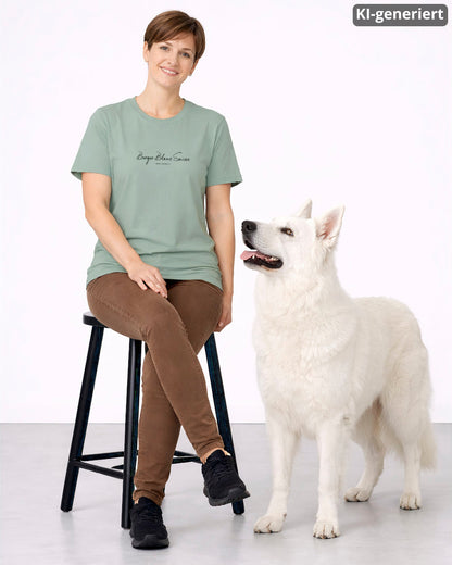 KI-generiertes Modelbild: Frau trägt Shirt in Aloe mit Brustmotiv "Berger Blanc Suisse. Was sonst?" und sitzt neben einem Berger Blanc Suisse.