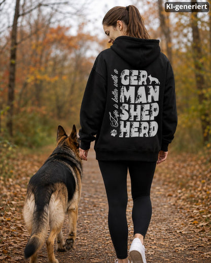 KI-generiertes Modelbild: Frau trägt schwarzen Oversized-Hoodie mit großem „Life is better with a German Shepherd“-Rückendruck und geht mit einem Deutschen Schäferhund im herbstlichen Wald spazieren.