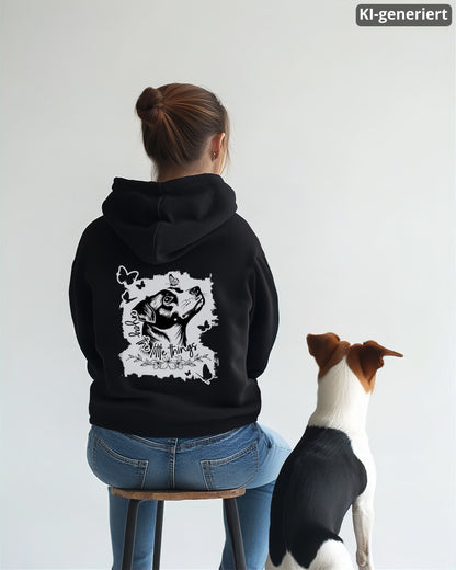 KI-generiertes Modelbild: Frau von hinten trägt schwarzen Hoodie mit Rückenmotiv „enjoy the little things“ und sitzt neben einem Jack Russell Terrier.