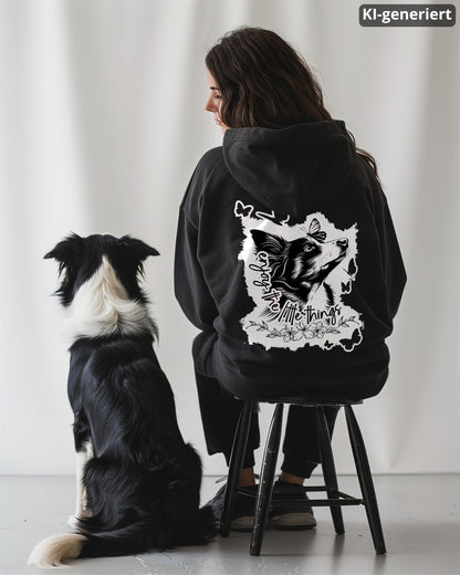 KI-generiertes Modelbild: Frau von hinten trägt schwarzen Oversized Hoodie mit Rückenmotiv „enjoy the little things“ und sitzt neben einem Border Collie.