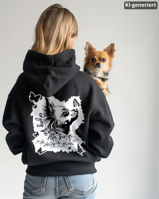 KI-generiertes Modelbild: Frau von hinten trägt schwarzen Oversized Hoodie mit Rückenmotiv „enjoy the little things“ und hält einen Chihuahua auf dem Arm.