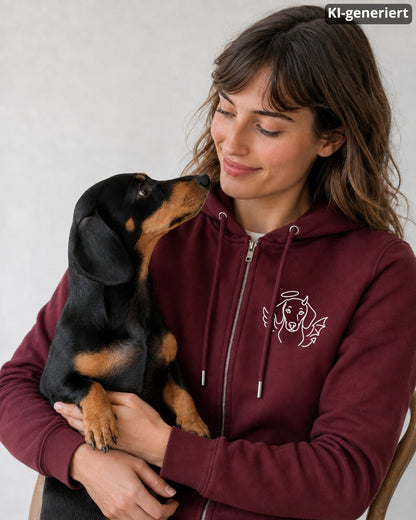KI-generiertes Modelbild: Frau in Burgundy Zip-Hoodie mit Engelchen-Teufelchen-Dackelmotiv, die einen schwarz-braunen Dackel auf dem Arm hält.