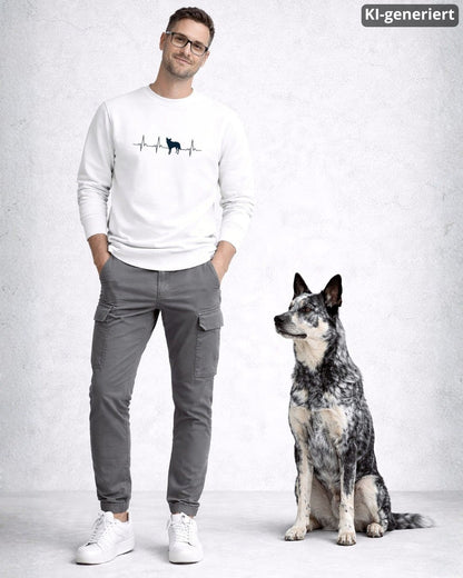 KI-generiertes Modelbild: Mann trägt weißen Sweater mit Australian-Cattle-Dog-Herzschlagmotiv und steht neben einem Australian Cattle Dog.