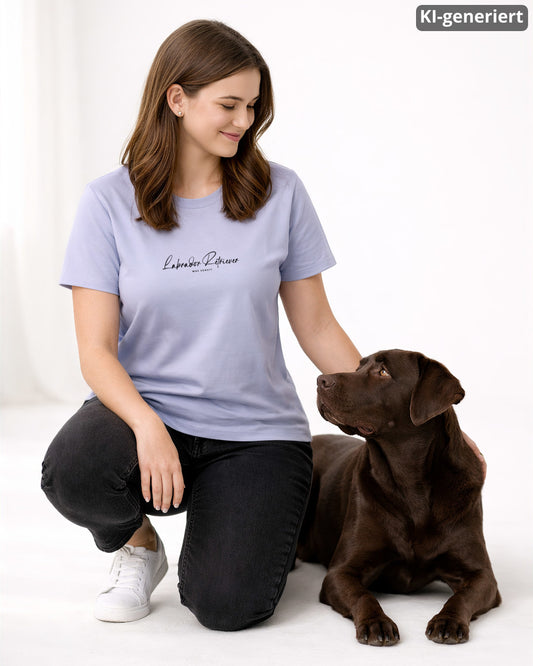 KI-generiertes Modelbild: Frau trägt lavenderfarbenes Shirt mit Labrador-Retriever-Schriftzug „Was sonst?“ und sitzt neben einem braunen Labrador.
