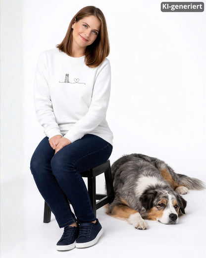 KI-generiertes Modelbild: Frau trägt weißen Sweater mit Australian-Shepherd-Linienmotiv mit Herz, daneben liegt ein Australian Shepherd.