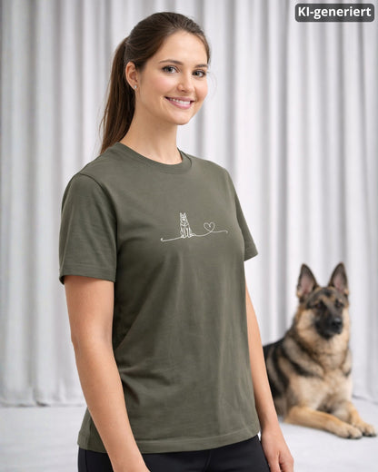 KI-generiertes Modelbild: Frau trägt khakifarbenes Shirt mit Deutscher-Schäferhund-Linienmotiv mit Herz, im Hintergrund liegt ein Deutscher Schäferhund.