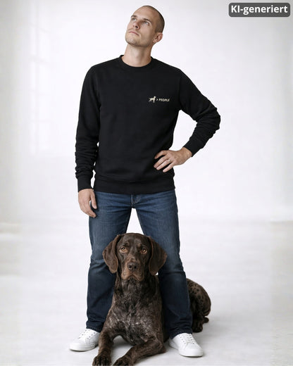 KI-generiertes Modelbild: Mann trägt schwarzen Sweater mit „Hund > People“-Brustmotiv und steht mit einem Deutsch Kurzhaar.