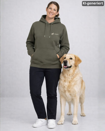 KI-generiertes Modelbild: Frau trägt khakifarbenen Hoodie mit „Hund > People“-Brustmotiv und steht neben einem Golden Retriever.