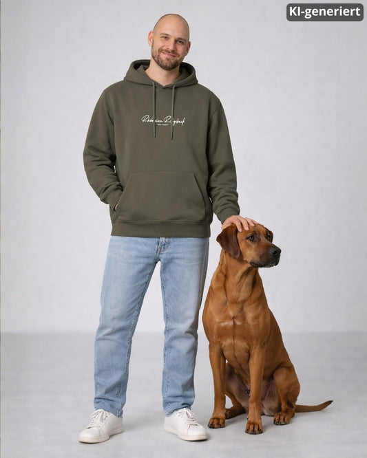 KI-generiertes Modelbild: Mann trägt khakifarbenen Oversized-Hoodie mit Rhodesian-Ridgeback-Schriftzug „Was sonst?“ und steht neben einem Rhodesian Ridgeback.